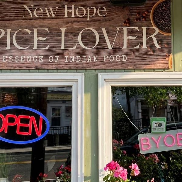 Exterior of New Hope Spice Lover, an Indian restaurant, with an "OPEN" neon sign and "BYOB" sign in the window.