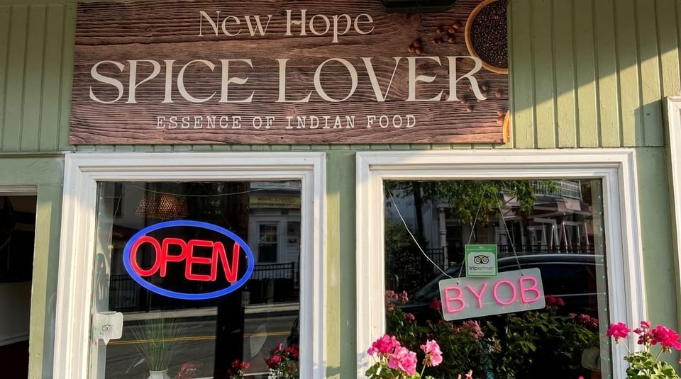 Exterior of New Hope Spice Lover, an Indian restaurant, with an "OPEN" neon sign and "BYOB" sign in the window.